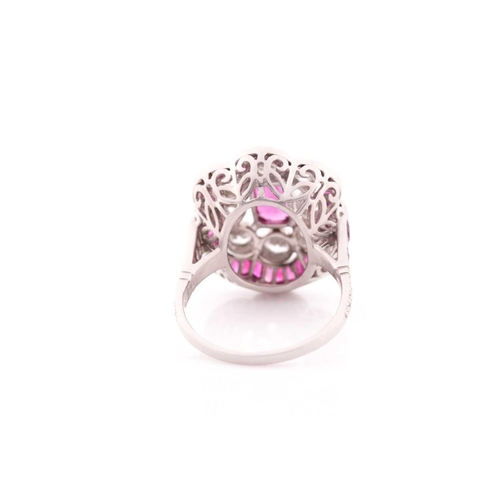 116 - A platinum, diamond, and ruby ring, the stylised mount centred with a mixed oval-cut ruby within a b... 