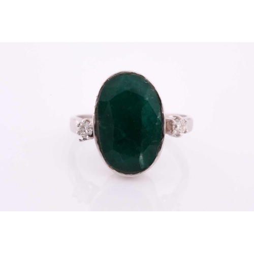 62 - An 18ct white gold, diamond, and emerald ring, set with a low grade mixed oval-cut emerald flanked w... 