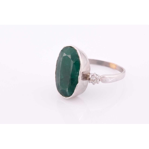 62 - An 18ct white gold, diamond, and emerald ring, set with a low grade mixed oval-cut emerald flanked w... 