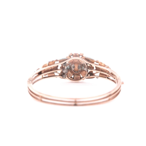 72 - An antique yellow metal and diamond bangle, set with a reddish pink central stone, likely spinel, th... 