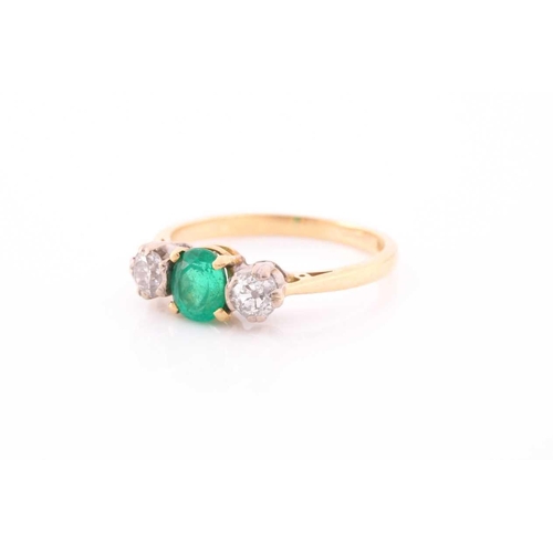 87 - A three stone half hoop emerald and diamond ring. The oval cut emerald in four claw mount flanked by... 