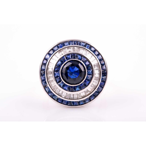 127 - A sapphire and diamond cluster ring; the central circular cut sapphire in rubover mount within conic... 