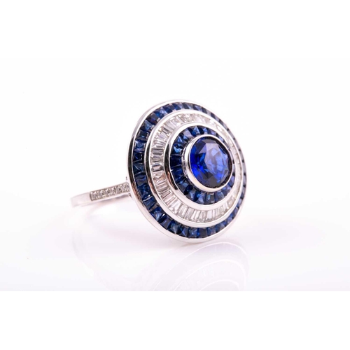 127 - A sapphire and diamond cluster ring; the central circular cut sapphire in rubover mount within conic... 
