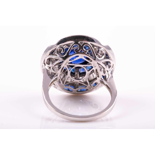 127 - A sapphire and diamond cluster ring; the central circular cut sapphire in rubover mount within conic... 