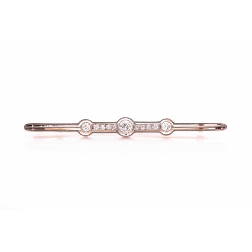 135 - An early 20th century yellow metal and diamond bar brooch, set with three collet-mounted round-cut d... 