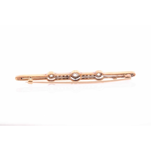 135 - An early 20th century yellow metal and diamond bar brooch, set with three collet-mounted round-cut d... 