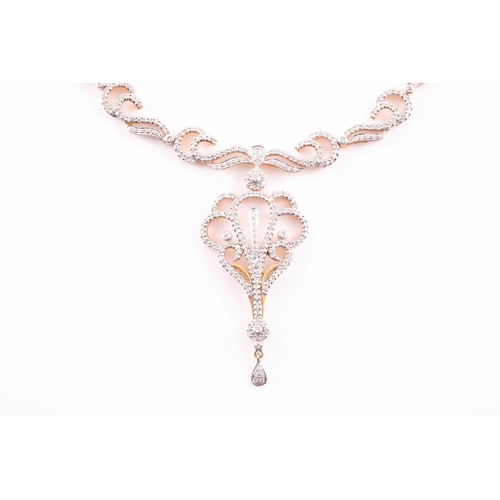 219 - An Indian diamond set necklace; the centre with a diamond set scrolling, openwork drop, from a circu... 
