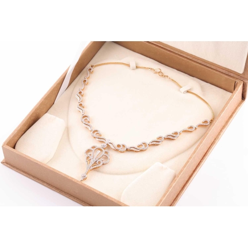 219 - An Indian diamond set necklace; the centre with a diamond set scrolling, openwork drop, from a circu... 
