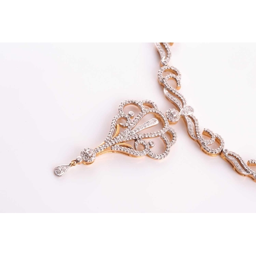 219 - An Indian diamond set necklace; the centre with a diamond set scrolling, openwork drop, from a circu... 