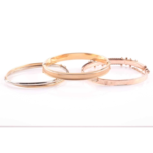69 - Three 9ct gold bangles, comprising; an Edwardian rose gold and gem set hollow rectangular-section hi... 