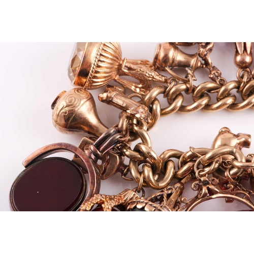 81 - A 9ct gold curb link ‘charm bracelet on a padlock clasp, London 1975, and hung with 16 various charm... 
