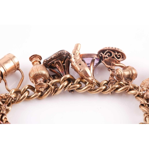 81 - A 9ct gold curb link ‘charm bracelet on a padlock clasp, London 1975, and hung with 16 various charm... 