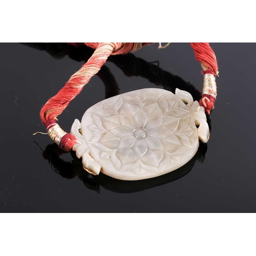 119 - An Indian white Jade necklace with oval central panel with yellow metal set red stones detail, the p... 