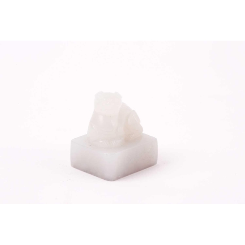 134 - A Chinese white jade seal, the seal of rectangular form surmounted by a recumbent lion dog, signed, ... 