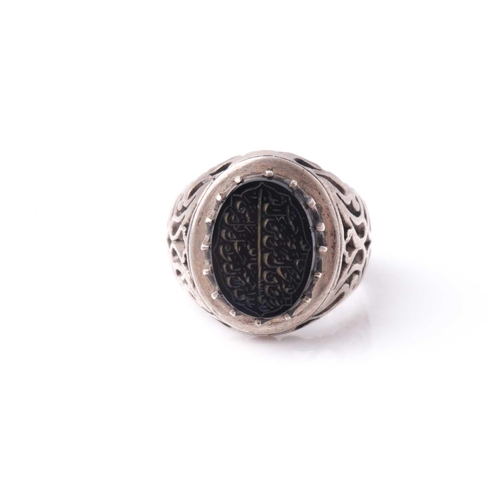 208 - An Eastern white metal and black onyx signet ring with pierced shoulders the oval stone with engrave... 