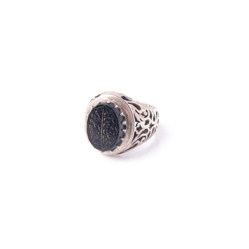 208 - An Eastern white metal and black onyx signet ring with pierced shoulders the oval stone with engrave... 