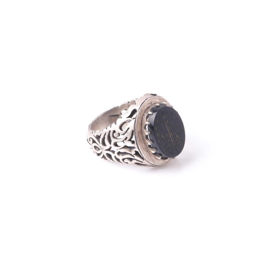 208 - An Eastern white metal and black onyx signet ring with pierced shoulders the oval stone with engrave... 