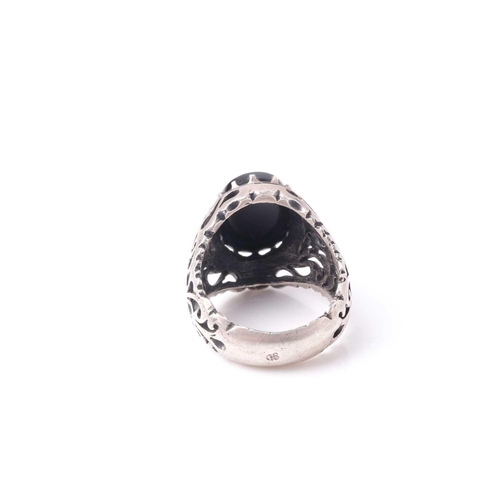 208 - An Eastern white metal and black onyx signet ring with pierced shoulders the oval stone with engrave... 