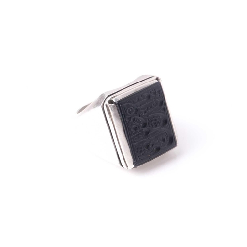 223 - An Eastern white metal and black onyx gentleman's ring, the rectangular stone with intaglio cut Isla... 