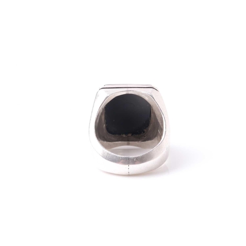 223 - An Eastern white metal and black onyx gentleman's ring, the rectangular stone with intaglio cut Isla... 