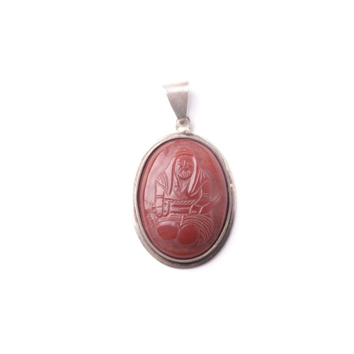 232 - A probably Middle Eastern oval white metal pendant inset with an agate panel carved with a seated ge... 