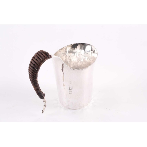 441 - A contemporary Japanese small silver jug, the s curved handle wrapped in bamboo, the planished body ... 