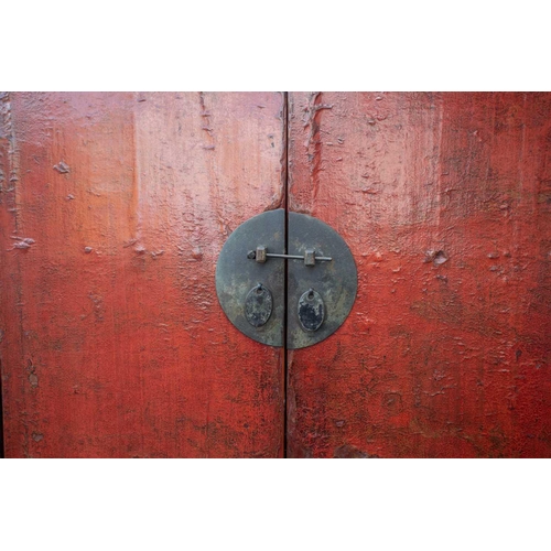 47 - A Chinese red lacquer cabinet, Qing, mid 18th century, the two doors joined by a circular escutcheon... 