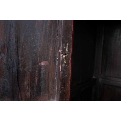 47 - A Chinese red lacquer cabinet, Qing, mid 18th century, the two doors joined by a circular escutcheon... 