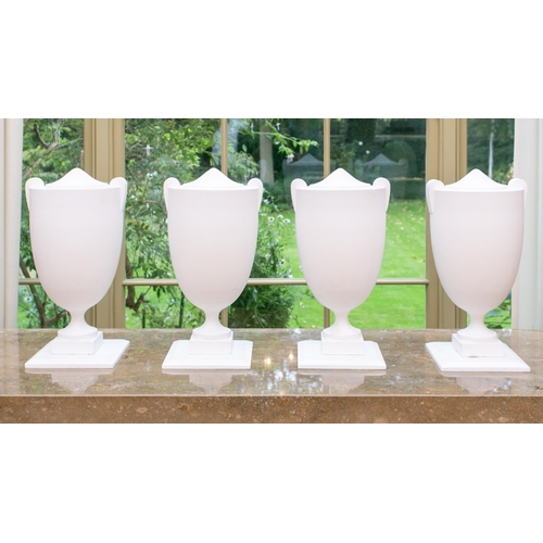 105 - A set of four white painted composition Hollywood Regency style urns of two handled form on stepped ... 