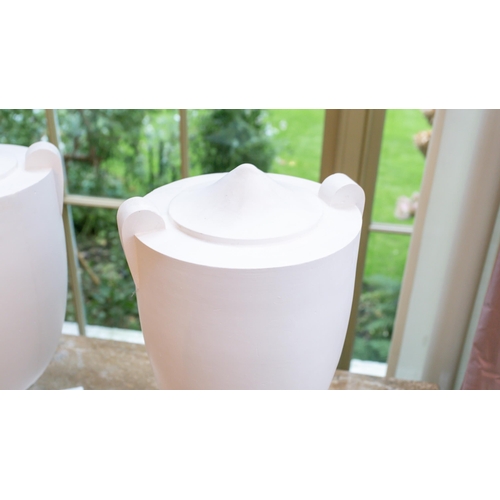 105 - A set of four white painted composition Hollywood Regency style urns of two handled form on stepped ... 