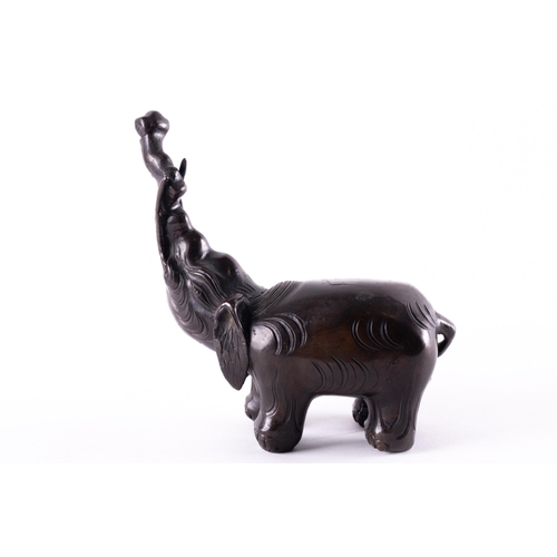 112 - A Chinese patinated bronze elephant figure of archaic form, with trunk held aloft. 765 grams. 13 cm ... 