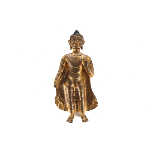 113 - A gilt bronze Buddha Shakyamuni, Nepal or Tibet, modelled standing in a long flowing robe, the hair ... 