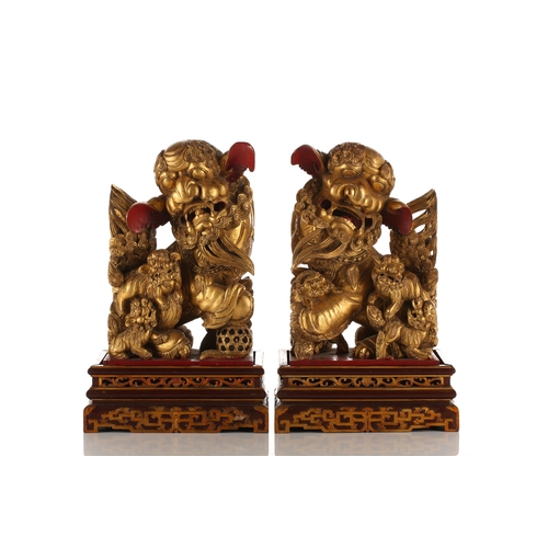 121 - A pair of Chinese carved and gilded wood temple lions and pups, each with characteristic scrolling m... 