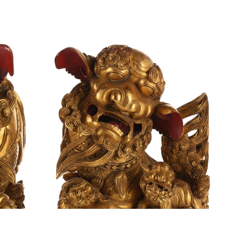 121 - A pair of Chinese carved and gilded wood temple lions and pups, each with characteristic scrolling m... 