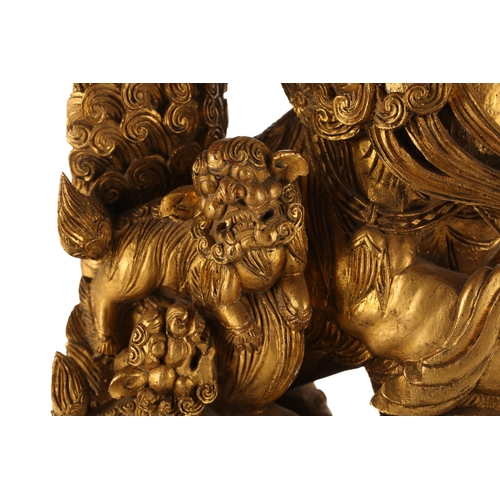 121 - A pair of Chinese carved and gilded wood temple lions and pups, each with characteristic scrolling m... 