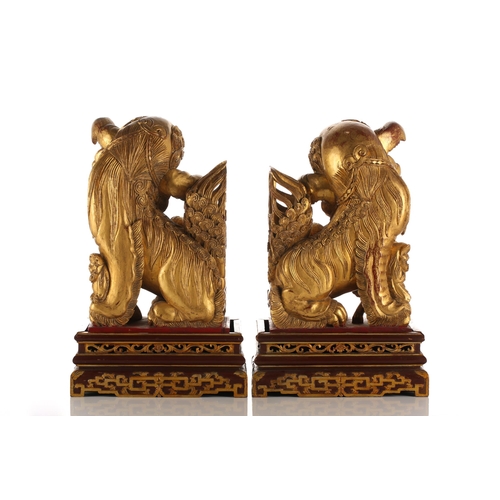 121 - A pair of Chinese carved and gilded wood temple lions and pups, each with characteristic scrolling m... 