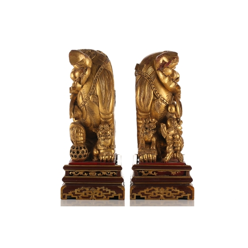 121 - A pair of Chinese carved and gilded wood temple lions and pups, each with characteristic scrolling m... 