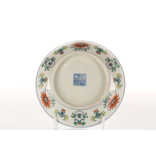 155 - A Chinese porcelain Doucai saucer dish, the centre painted with a flower bordered by repeating frond... 