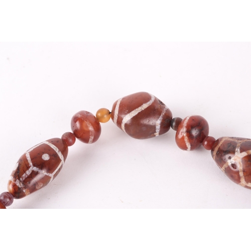 190 - A string of dark amber coloured Dzi type polished stone beads, 60.5cm long