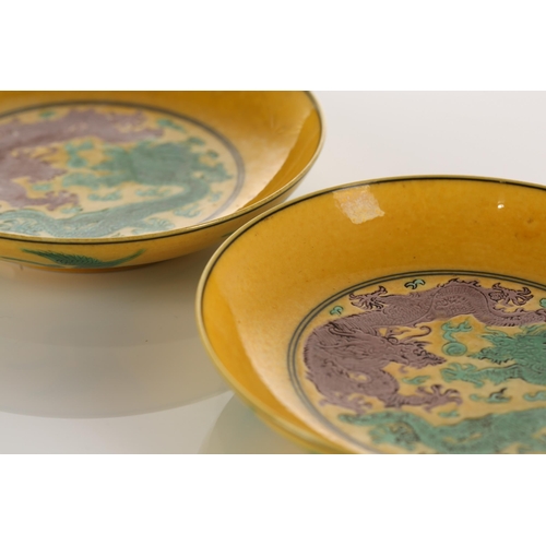 191 - A pair of Chinese porcelain dragon dishes, each with an incised green and aubergine dragon against a... 