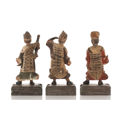 197 - Three Chinese carved wood and polychrome temple guardians, Qing dynasty, on carved wood base, 26cm