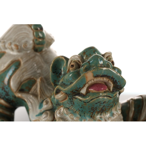 208 - A pair of Shiwan pottery temple lions, 20th century, each modelled in a playful pose, their left paw... 