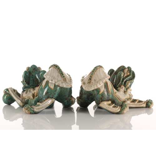 208 - A pair of Shiwan pottery temple lions, 20th century, each modelled in a playful pose, their left paw... 