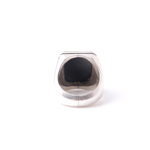 241 - An Eastern white metal and black onyx gentleman's ring, the rectangular stone with intaglio cut Isla... 