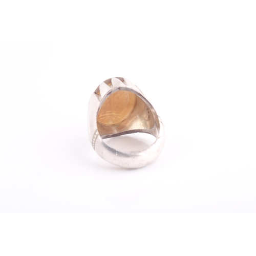 252 - An Indo Persian white metal and hardstone ring, set with a pale orange onyx hardstone with engraved ... 