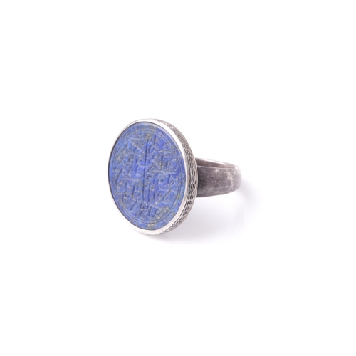 255 - A probably Persian white metal dress ring set with a circular lapis lazuli panel engraved with Islam... 