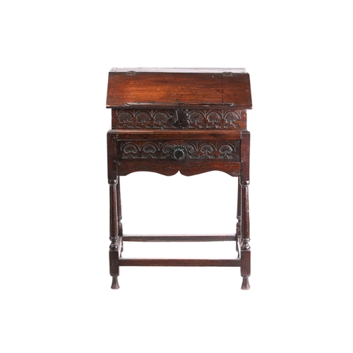 302 - An early 18th century carved oak slope fronted bible box with a simple fitted interior. On a later o... 