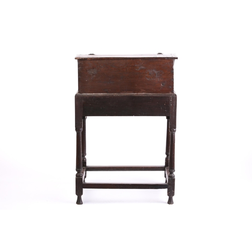 302 - An early 18th century carved oak slope fronted bible box with a simple fitted interior. On a later o... 