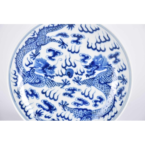 267 - A Chinese blue & white saucer dish, painted with two opposing dragons facing a flaming pearl amongst... 