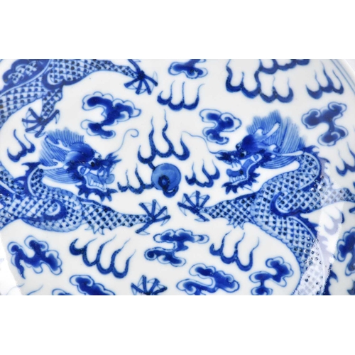 267 - A Chinese blue & white saucer dish, painted with two opposing dragons facing a flaming pearl amongst... 